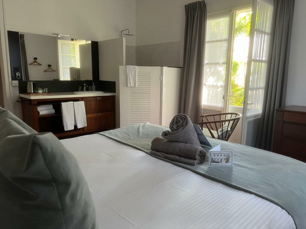 Lit double de la chambre Muriel, avec la vasque et la douche à l'italienne en arrière-plan — Villa Myriam, Saint-Pierre
