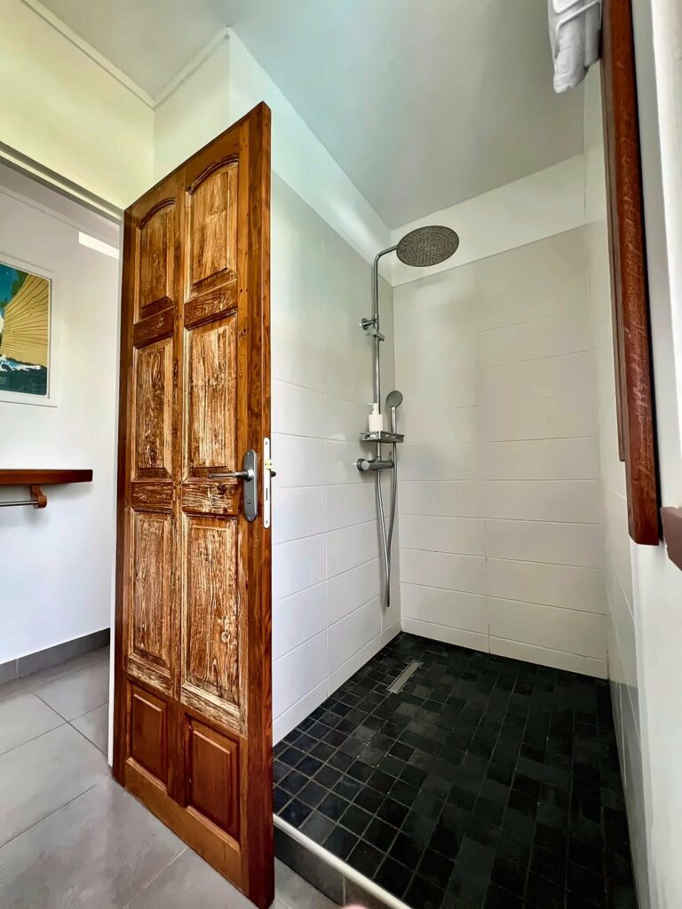 Douche à l'italienne de la chambre Chloé, derrière une porte créole ancienne — Villa Myriam, Saint-Pierre