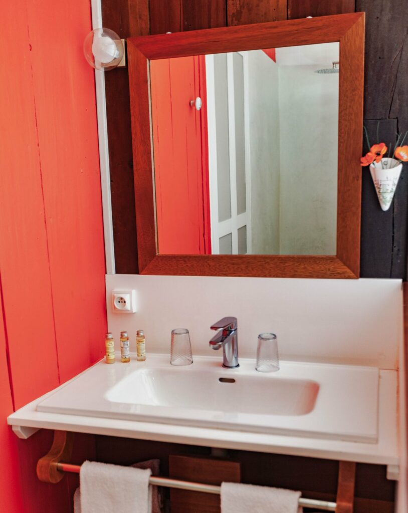 Vasque et miroir de la salle d'eau de la chambre Marie, mur rouge — Villa Myriam, Saint-Pierre