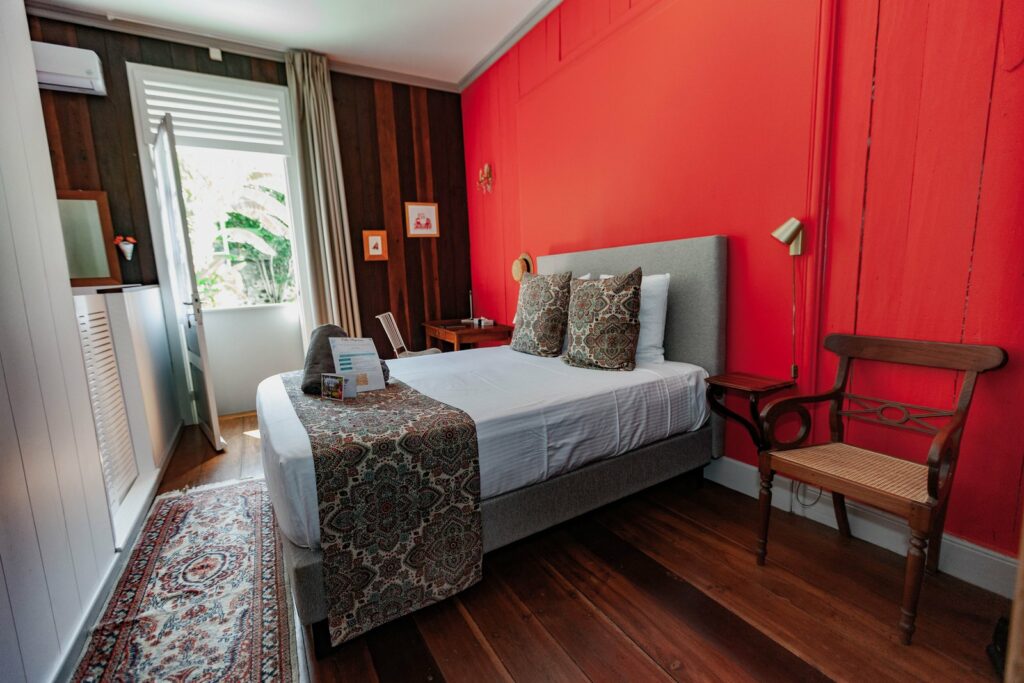 Vue d'ensemble de la chambre Marie, murs rouges, lit queen size et fenêtre sur le jardin — Villa Myriam, Saint-Pierre